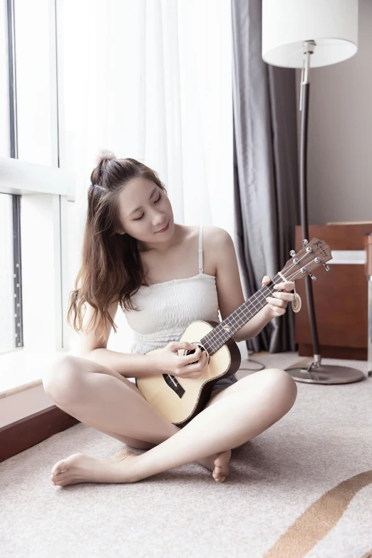 the girl sitting on the floor playing the guitar