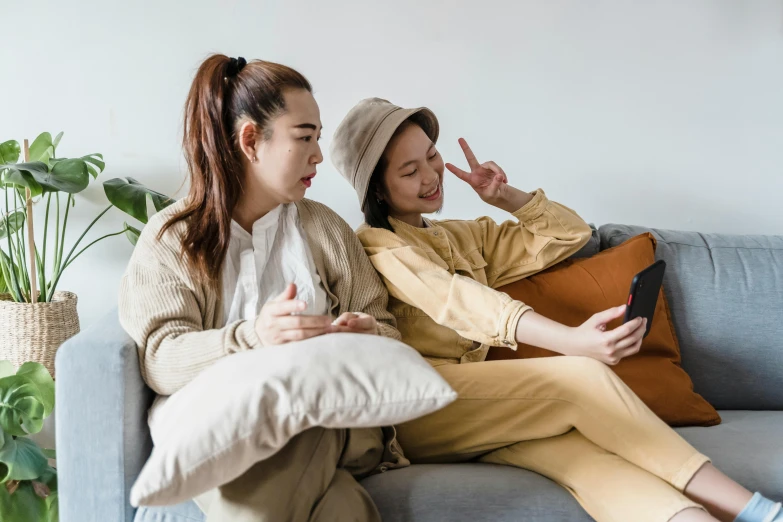 two asian women are looking at soing while they are sitting on a couch