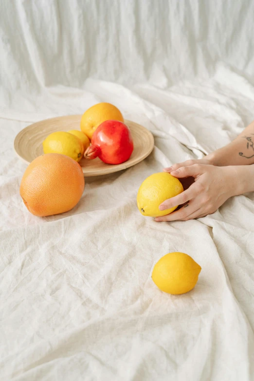 woman holding a fruit in her hand on a bed