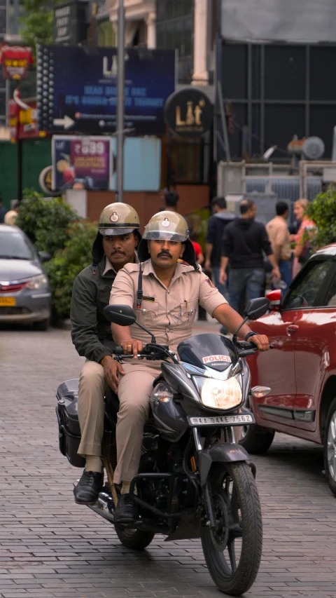 two uniformed officers are riding a motorcycle down the street