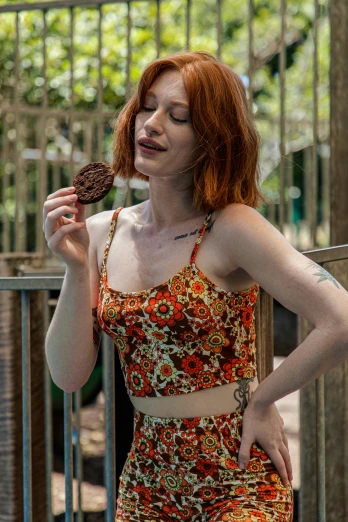 woman in a orange and green patterned bathing suit, holding a donut