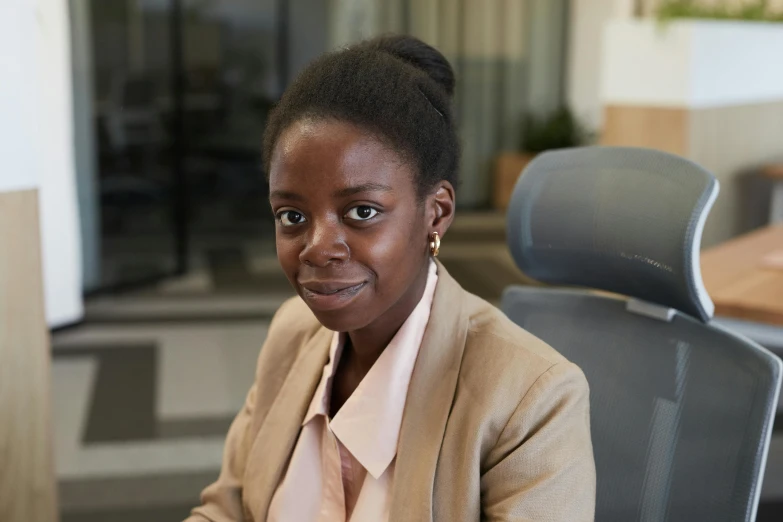 a woman sitting at a desk wearing a jacket and tie