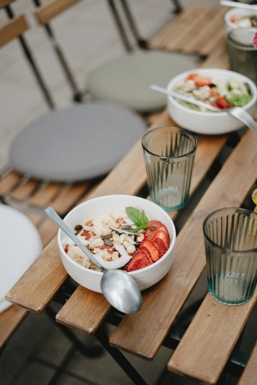 a table with four bowls, silverware and several forks and spoons