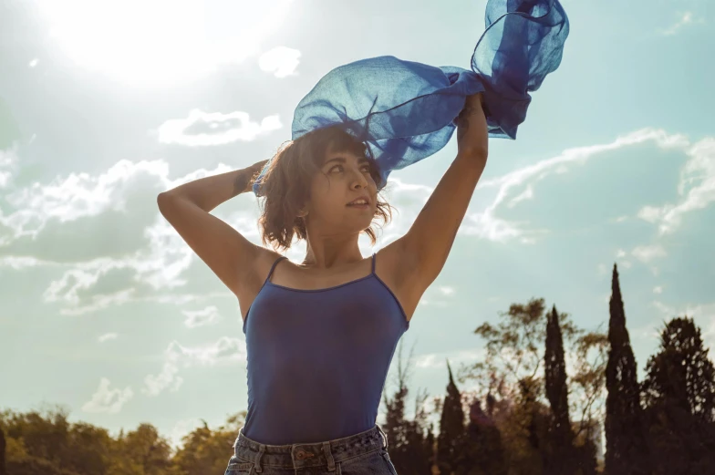 a woman is standing in a field with a blue scarf