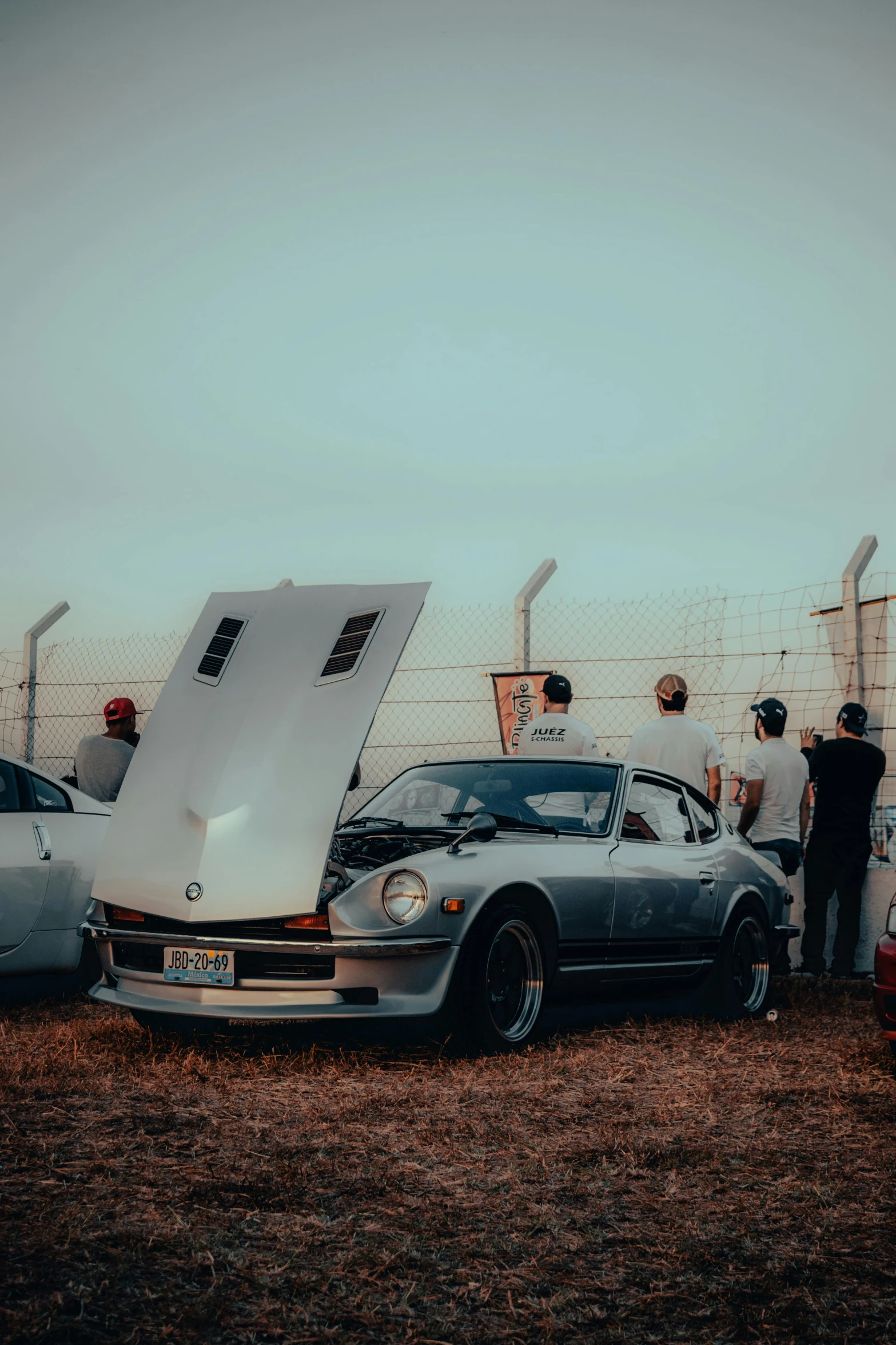 men standing around looking at broken down car