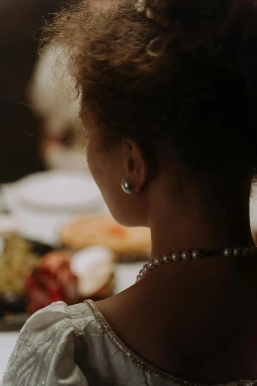 woman in white dress staring across dinner table