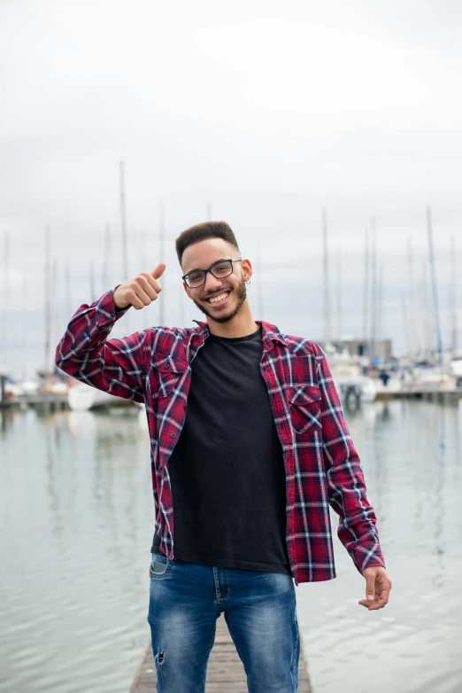 a young man standing at a dock gives a thumbs up