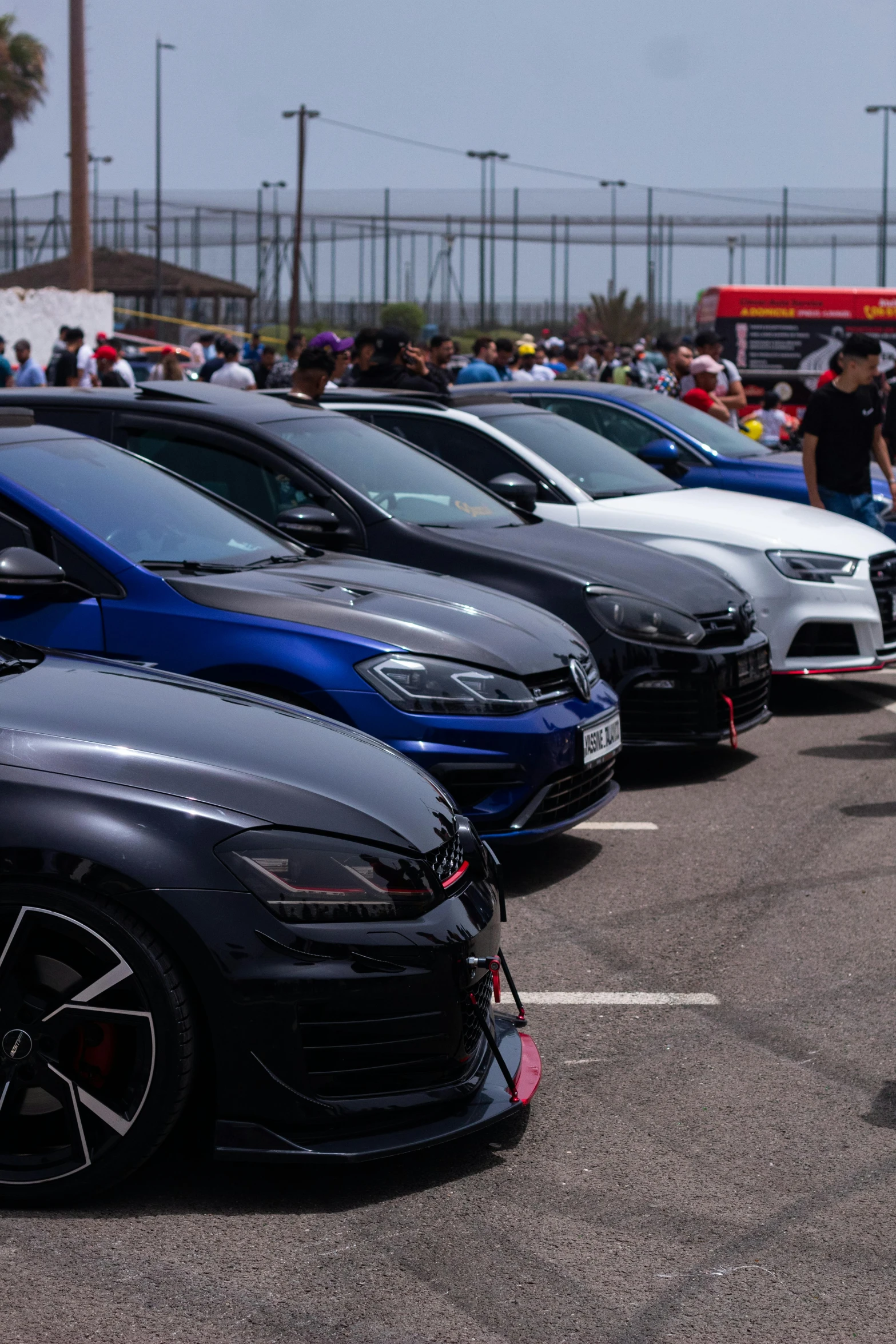 a line of cars in a parking lot with people in the background