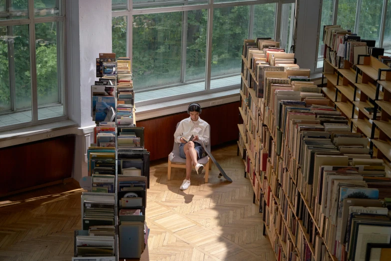 the person is sitting on a chair in front of a huge number of books