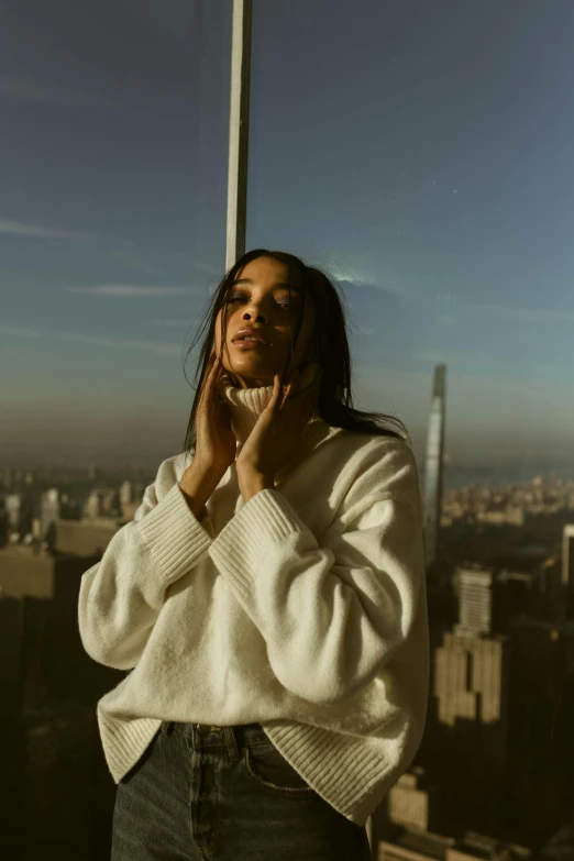 a woman poses next to a pole with a large city in the background