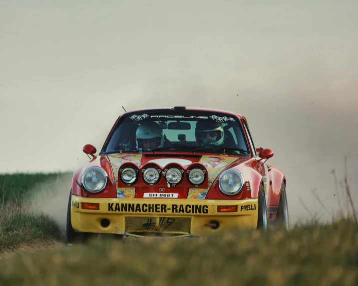 the red car is driving along the dirt road