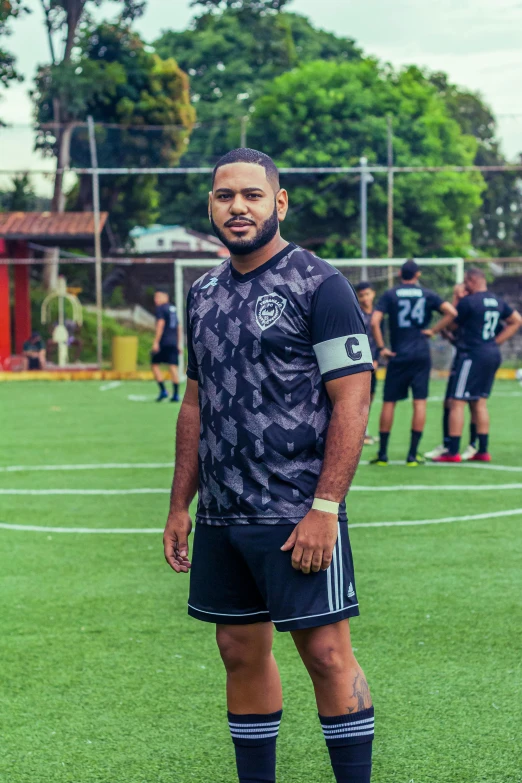 a young black man standing in front of a soccer field