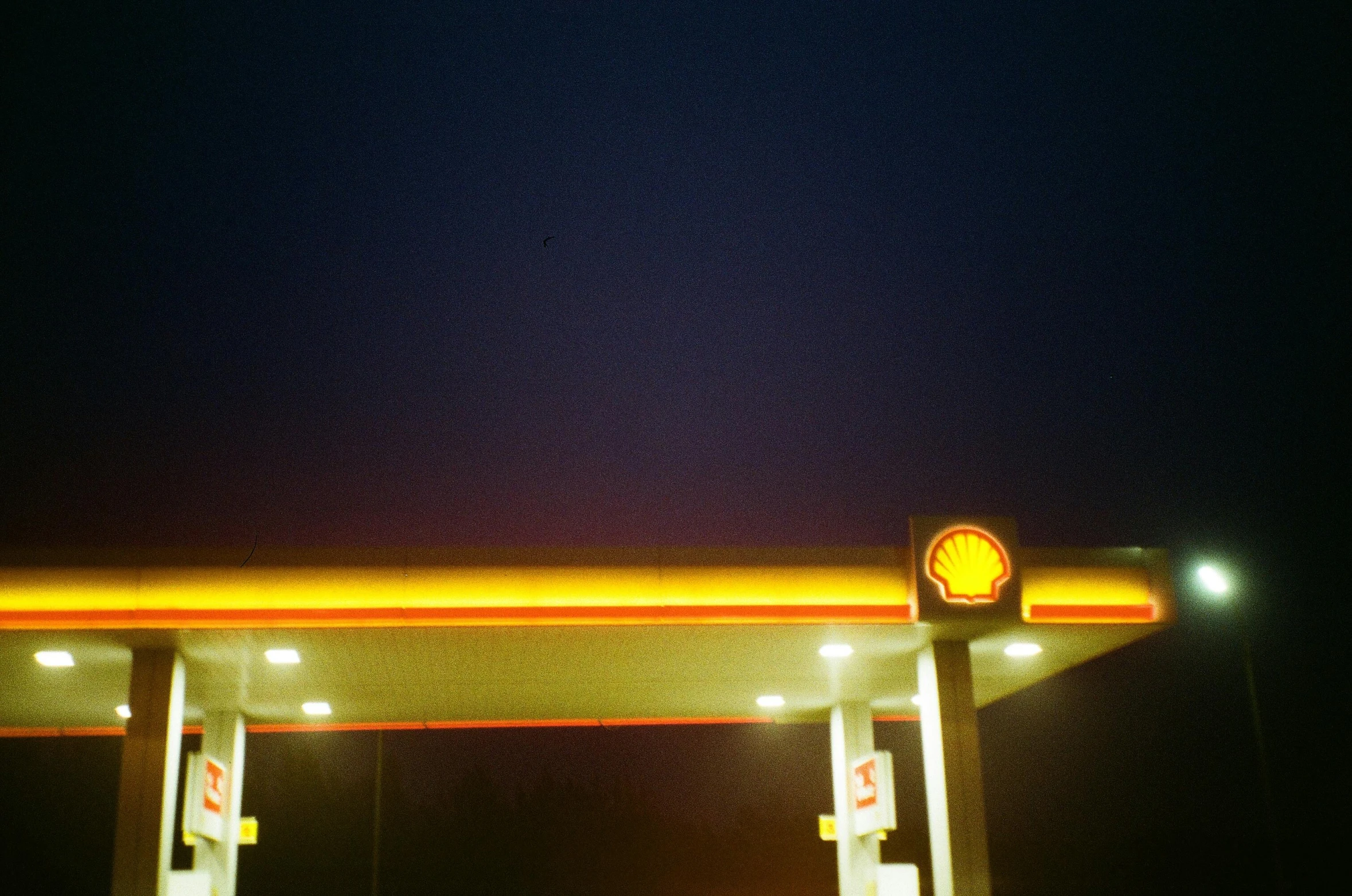a bright yellow sign on a gas station wall