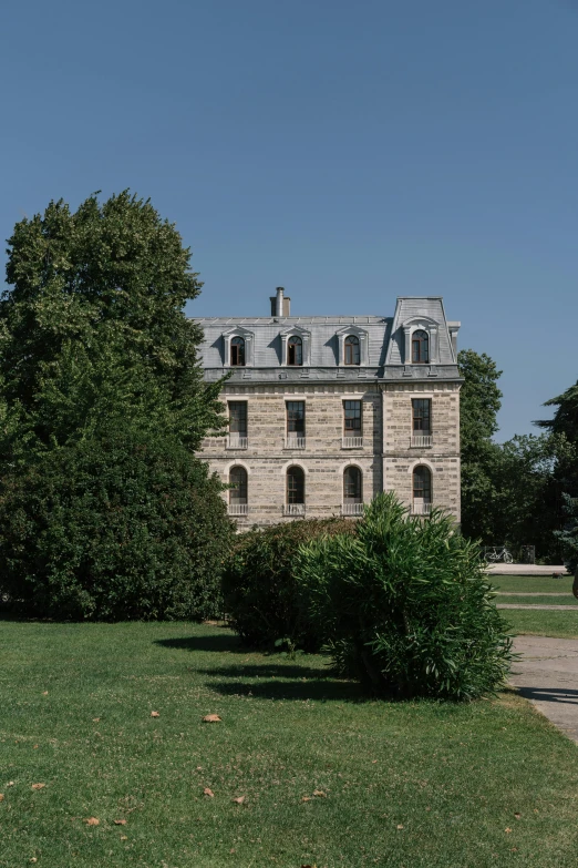 a brown and gray stone building surrounded by green trees