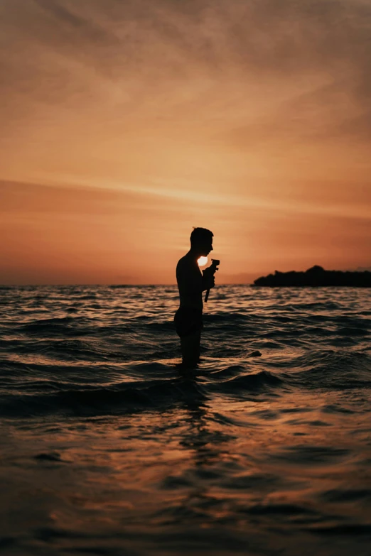 a man standing on a surfboard at sunset