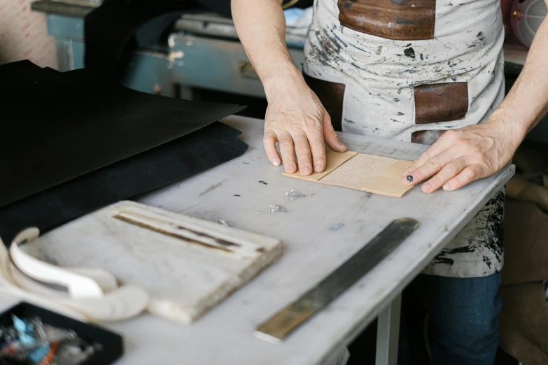 woman in apron using edge trimming machine in workshop