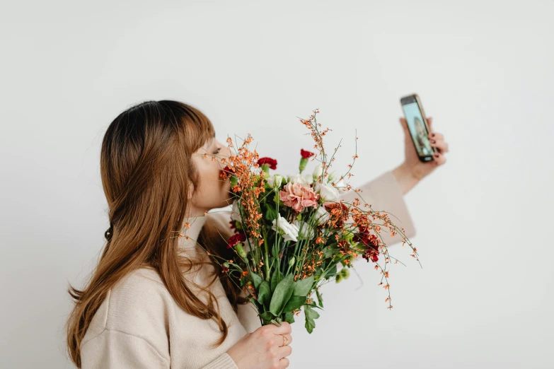 a woman holding a bouquet while holding a cell phone