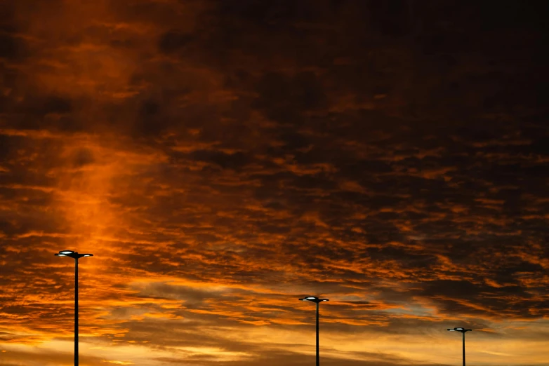 the lights are shining brightly at sunset under clouds