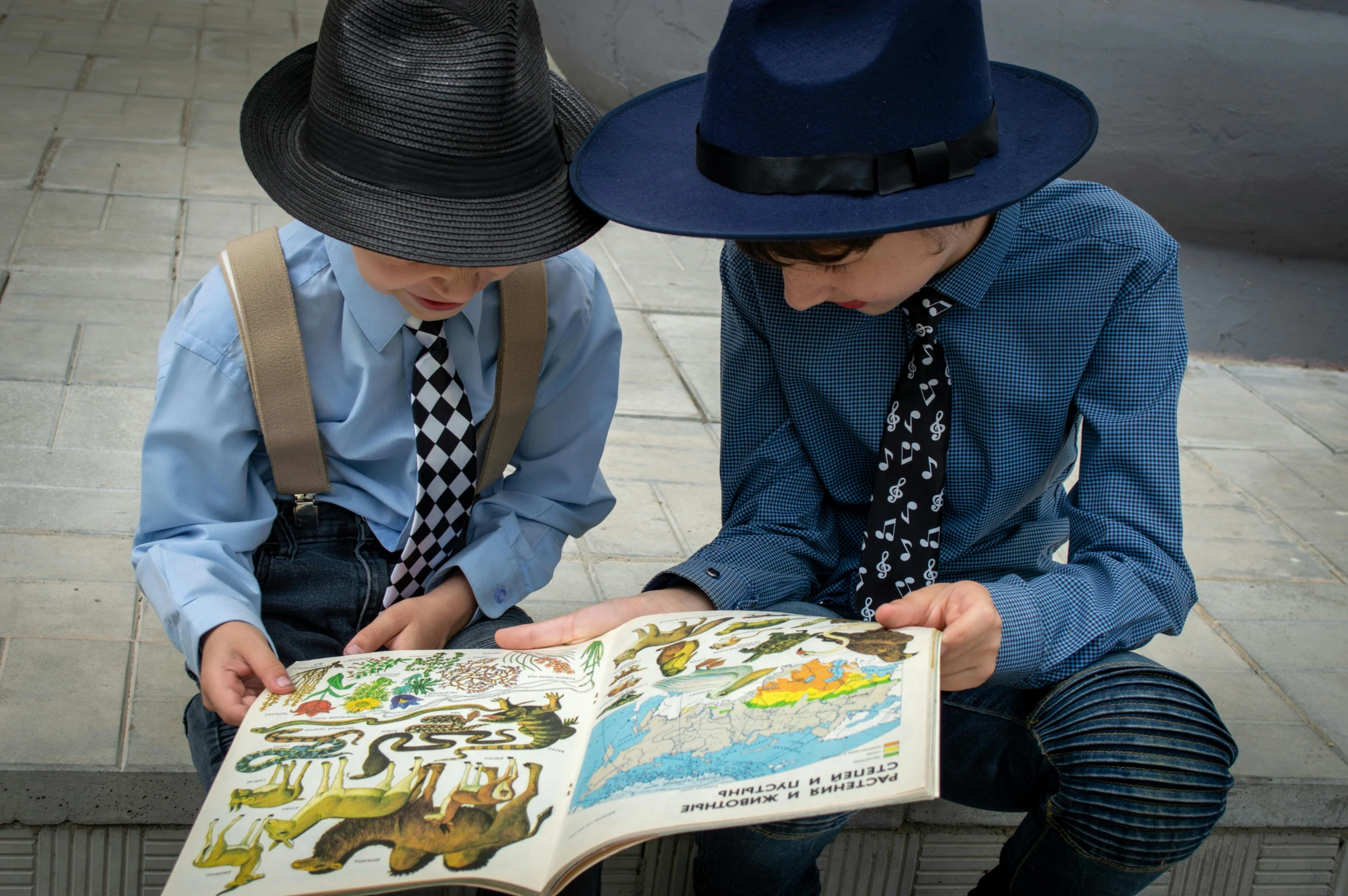 two s are sitting on steps and reading