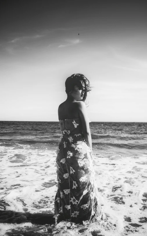 a woman standing in the surf at a beach