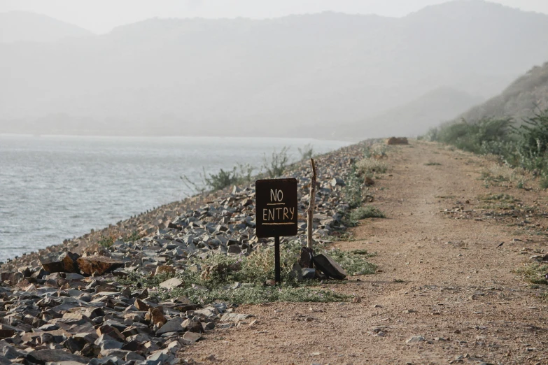 a sign that is near some rocks by the water