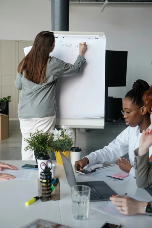 several people in a meeting are looking at the whiteboard