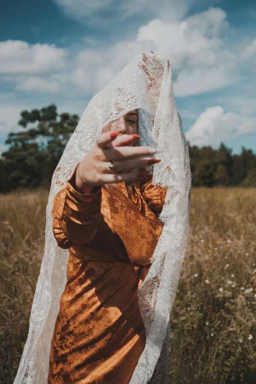 a woman in an orange dress poses with her hand in a shawl