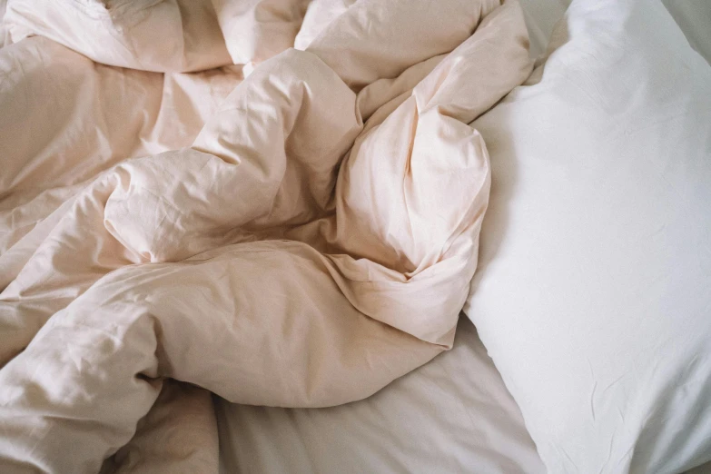 an unmade bed with white sheets and pillow