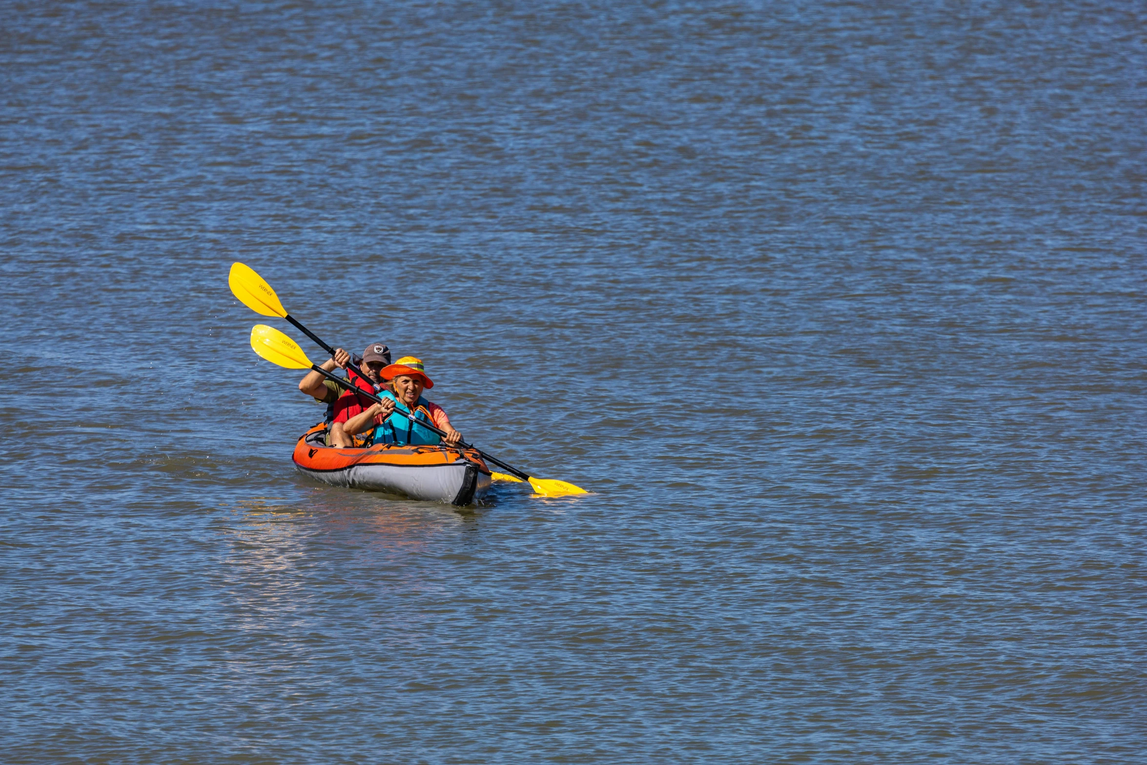three people are paddling on kayaks in the middle of the ocean
