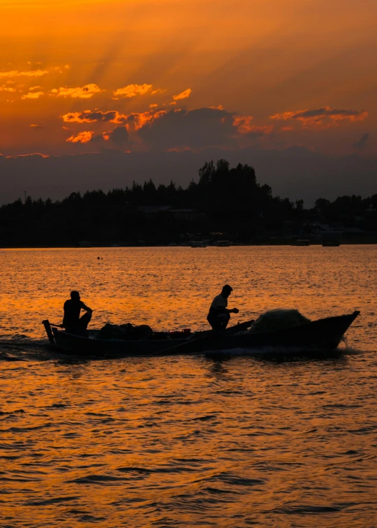 two people in a boat on the water at sunset