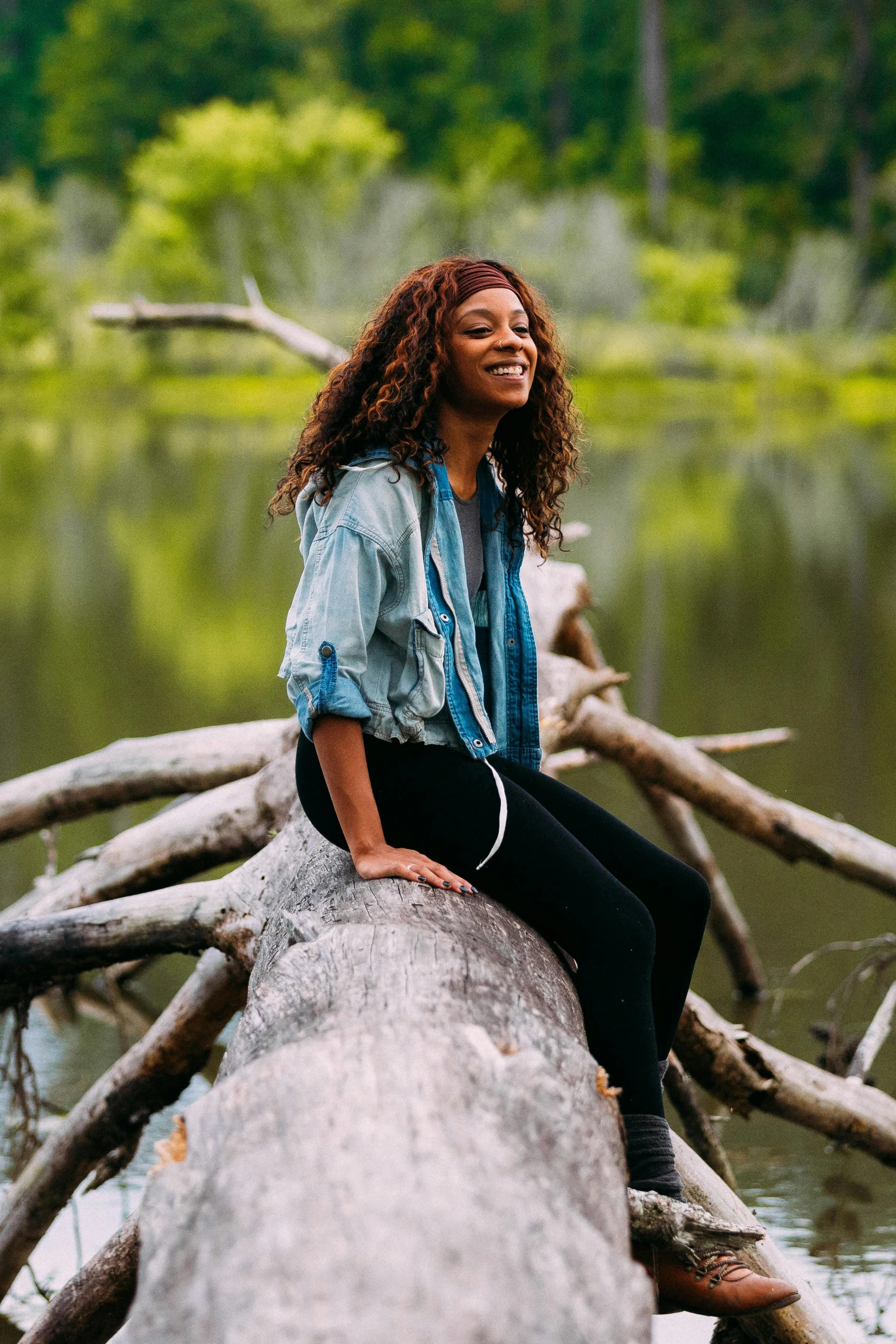 a woman sitting on a log in the woods