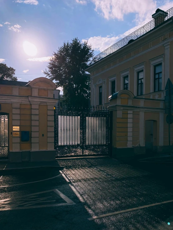 a building with a gate near it and the sun behind