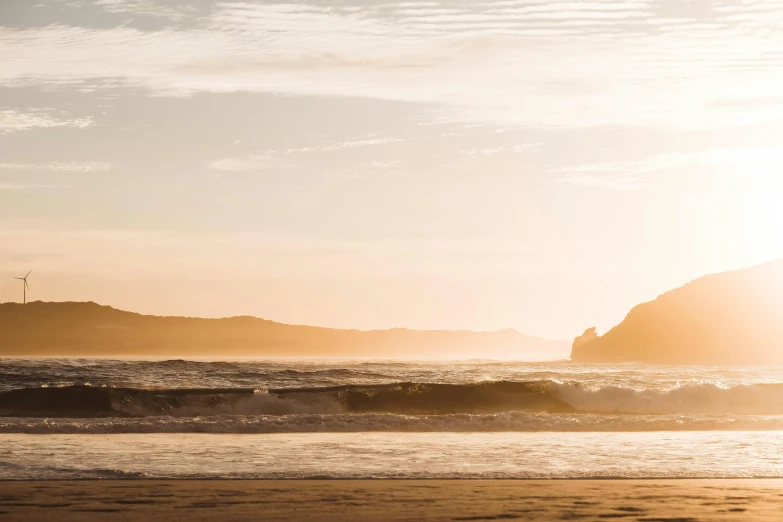 a man riding a surfboard on a beach in the sunset