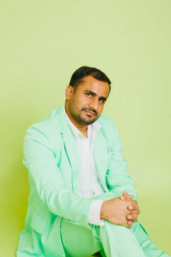 a man in a green suit poses for a pograph