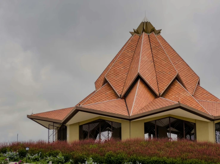 a red brick covered structure with flowers and grass around it