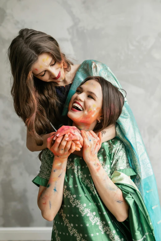 two little girls covered in color laughing and playing