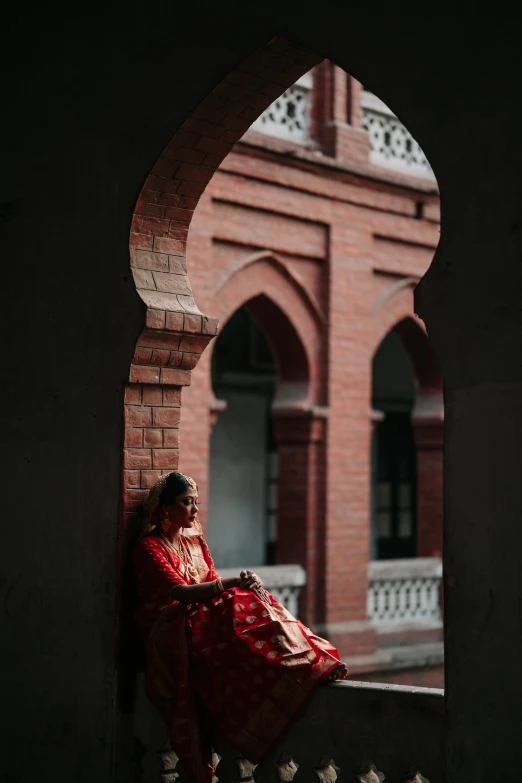 a woman in a red dress sits on a wall with her legs crossed