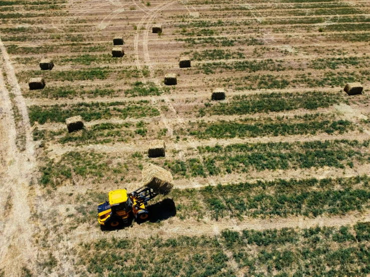 a tractor is driving on a patch of hay