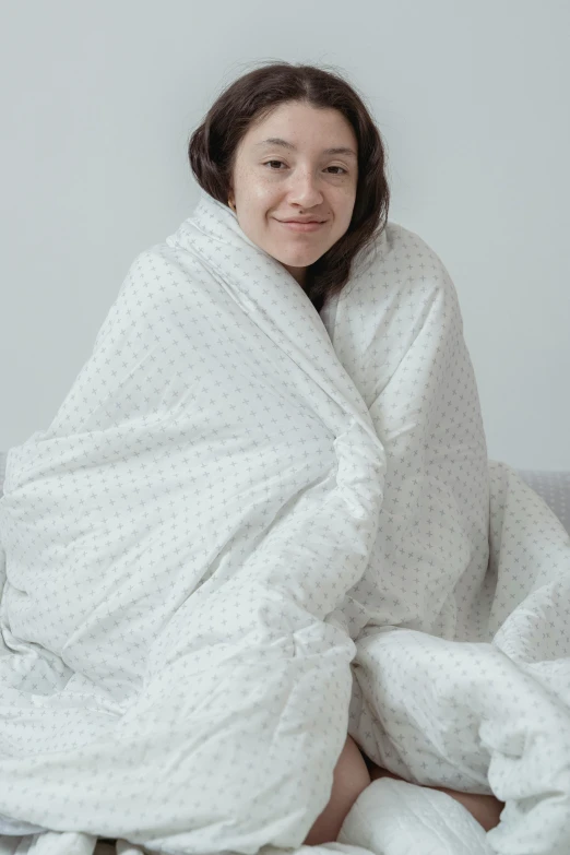 woman wrapped in a white blanket sitting in bed