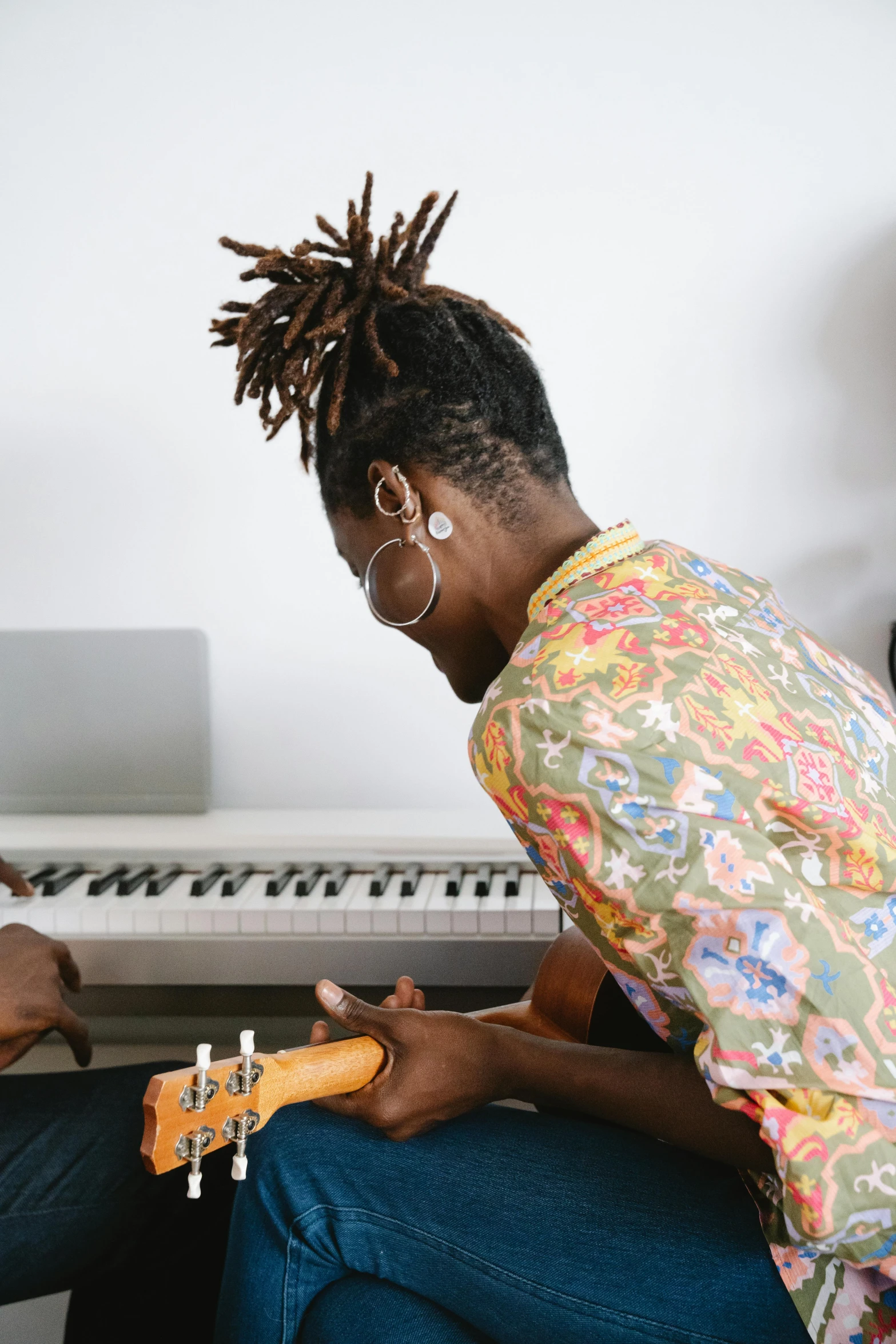 a woman sitting in front of a keyboard playing the guitar