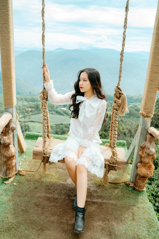 a girl is sitting on a swing with two handles