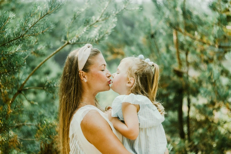 two girls are kissing each other in front of trees