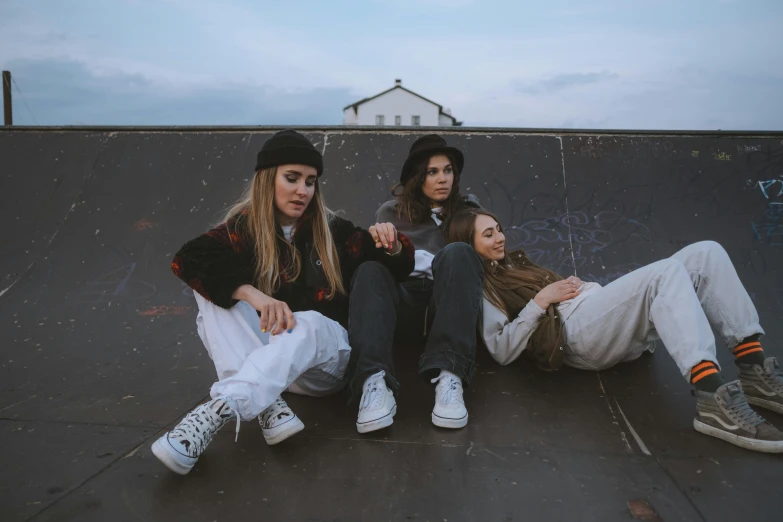 three s in white jackets sitting on a skateboard ramp