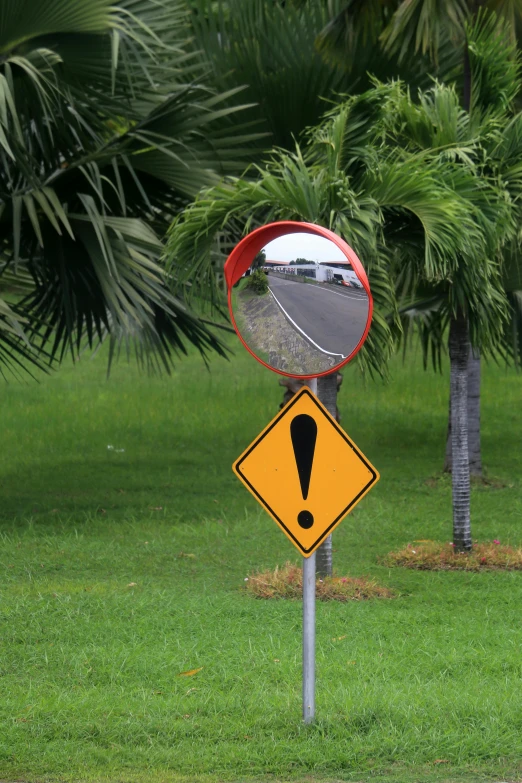 a yellow traffic sign with a round mirror on it