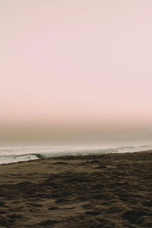 a lone surfer standing at the edge of the ocean