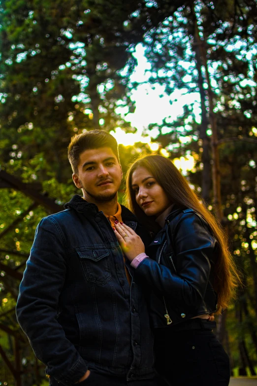 a man and woman pose for a picture in front of trees