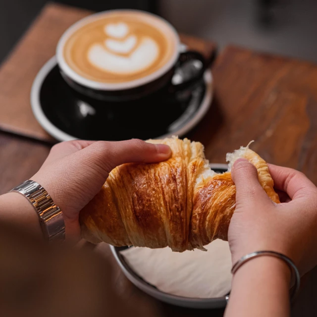 someone holding a croissant and looking down at the camera