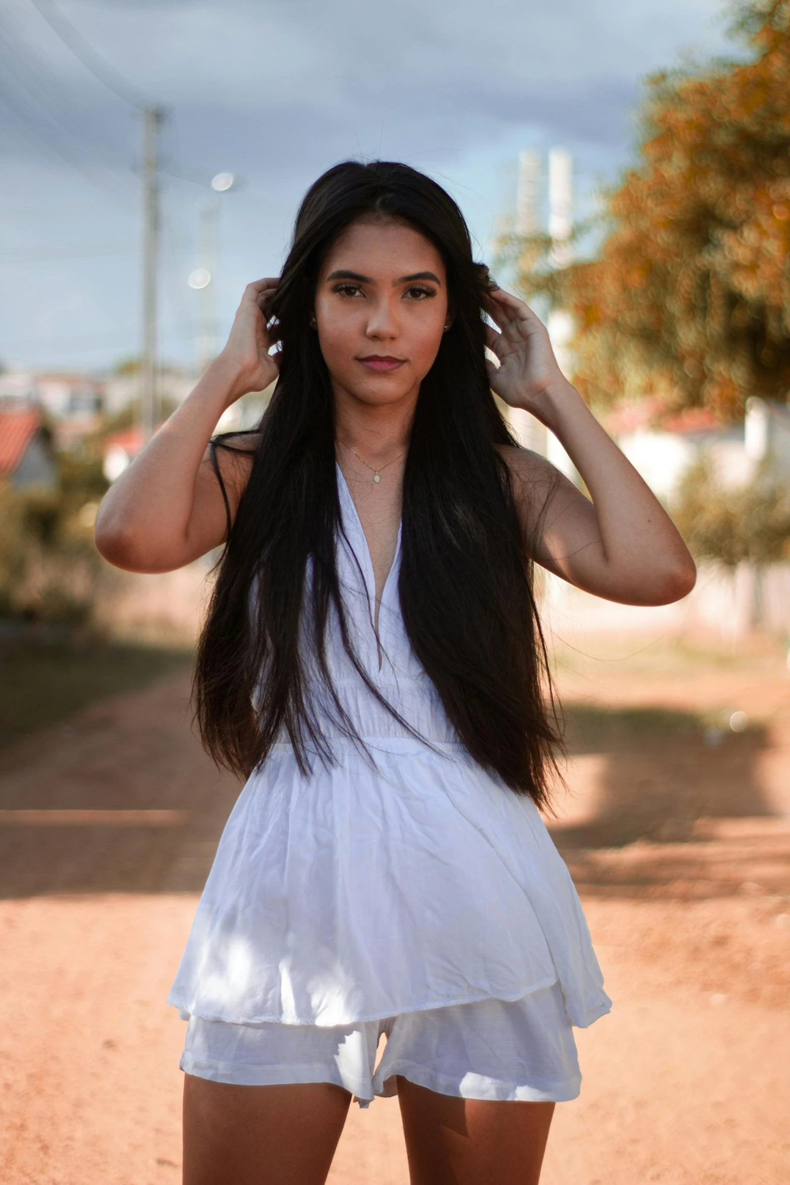 a woman standing on dirt road with long black hair