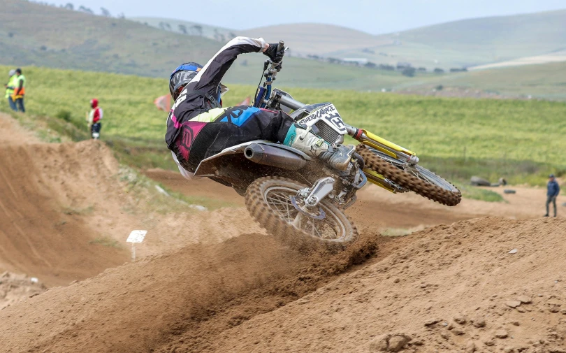 person riding dirt bike on track with other people watching