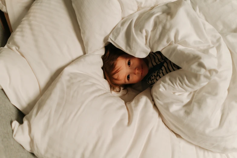 a girl under the blanket on her bed